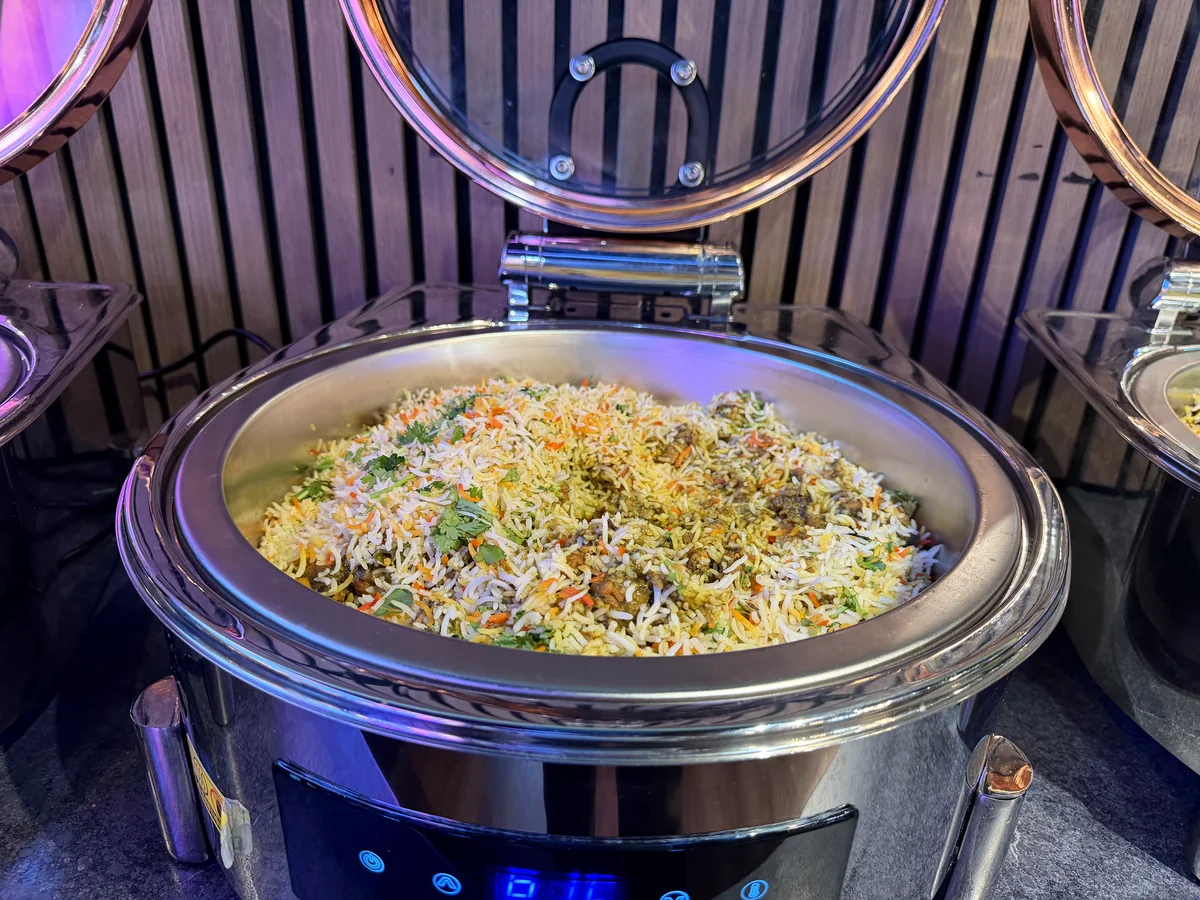Goat biryani served in a round buffet chafing dish