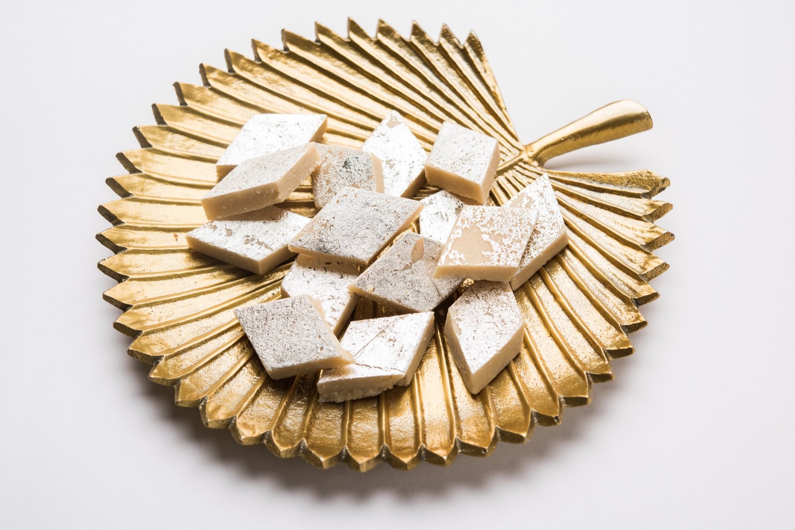 Silver kaju katli arranged on an ornate golden platter